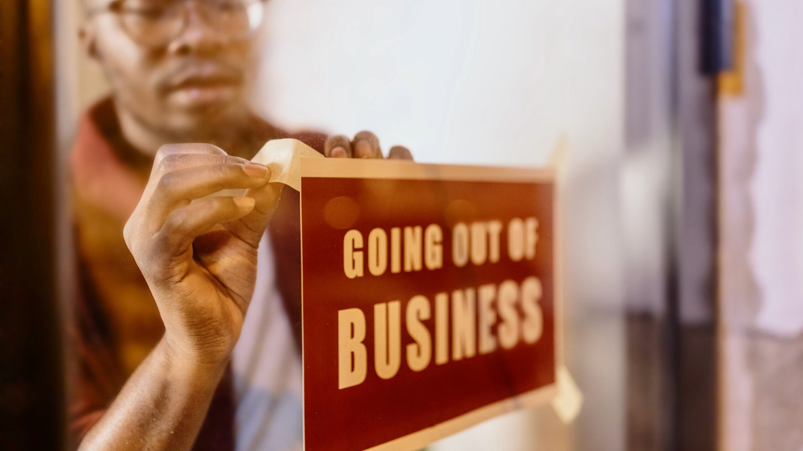 African-American business owner putting up a sign in the window saying 